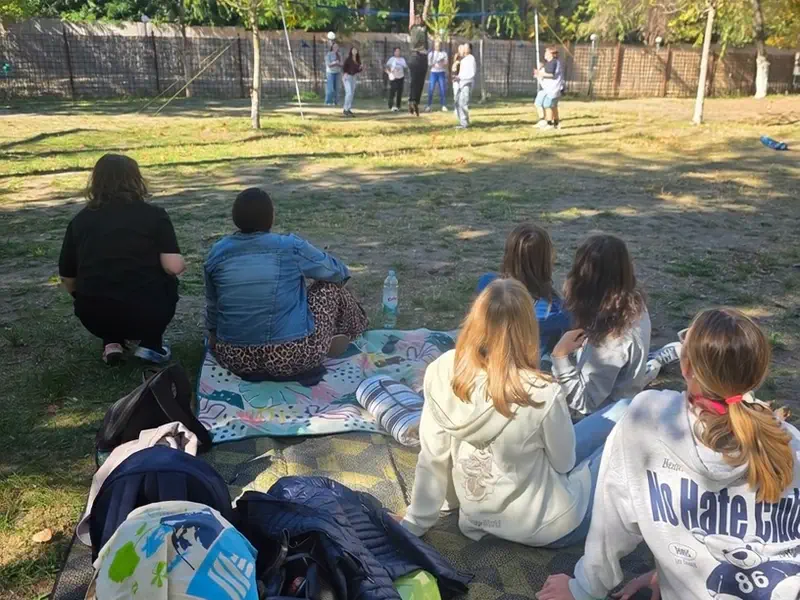 Pihenő a pokrócon, a háttérben játszó diákok